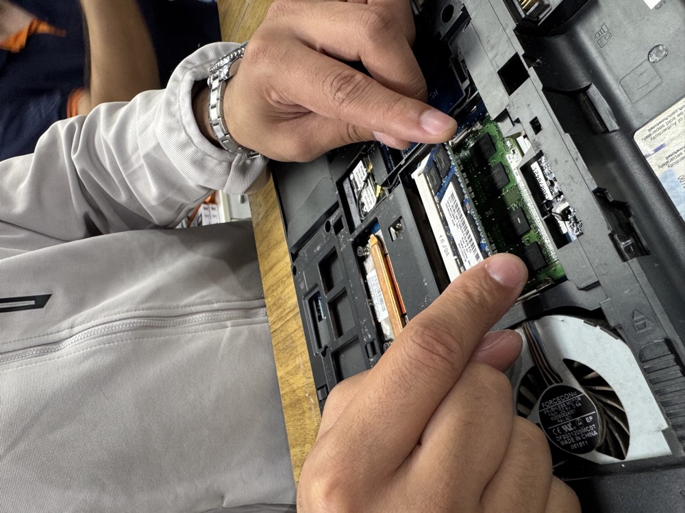 Detalhe das mãos manuseando um módulo de memória RAM em um notebook aberto